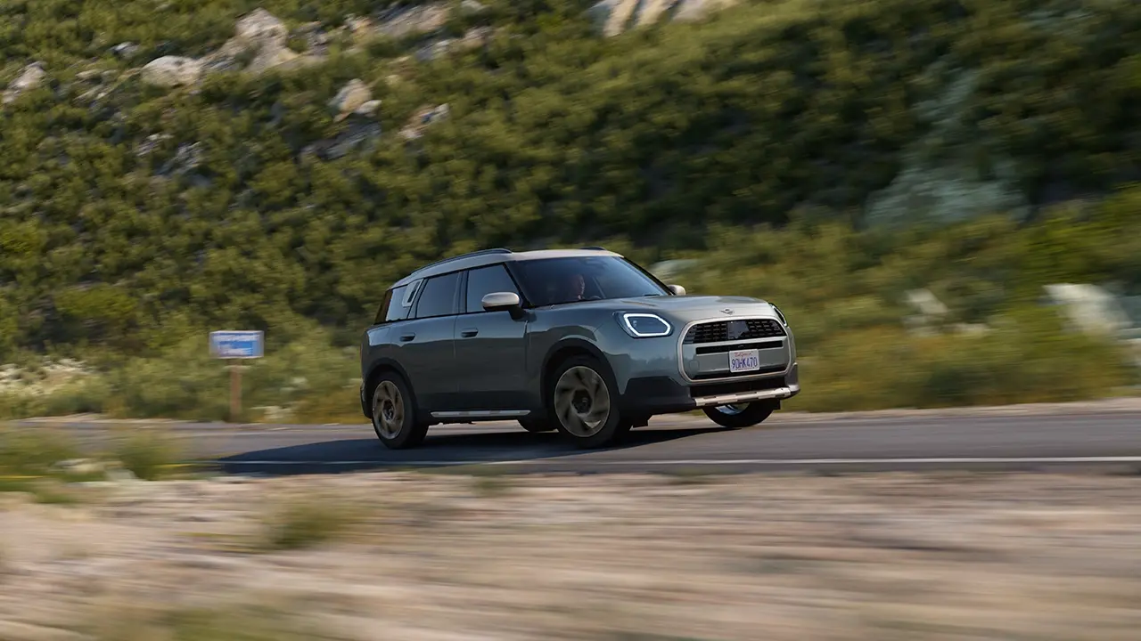 Vedere a MINI Countryman de culoare Smokey Green și Favoured Style conducând off-road