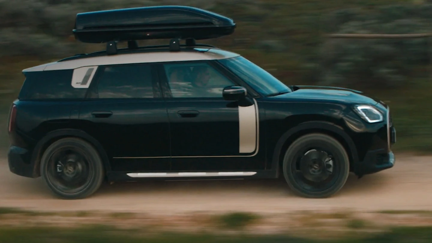 MINI Countryman de culoare Midnight Black metalizat, cu jante de 19" spiţate John Cooper Works Runway de culoare neagră, deplasându-se pe teren accidentat. 