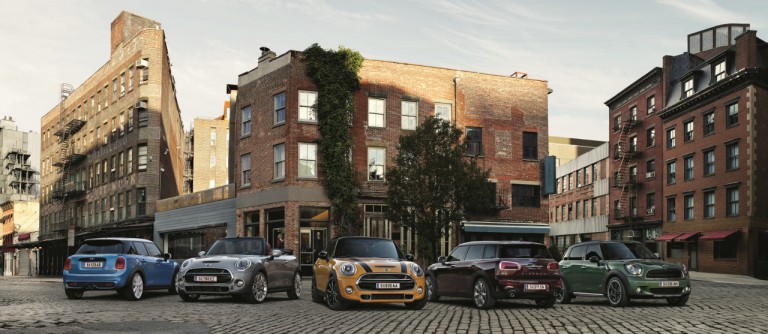 Cinci automobile MINI în faţa unor clădiri, într-un peisaj urban